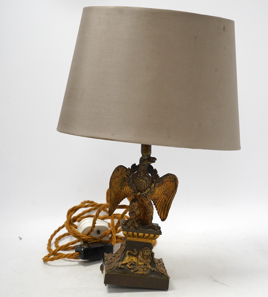 An ormolu table lamp in the form of an eagle with a laurel wreath around its neck, fitted with a grey shade, 39cm high overall. Condition poor to fair, three feet missing to lamp